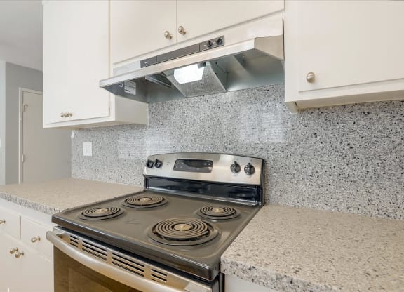 a kitchen with white cabinets and a stove top oven