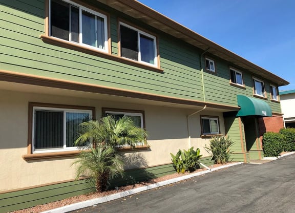 a green house with palm trees in front of it