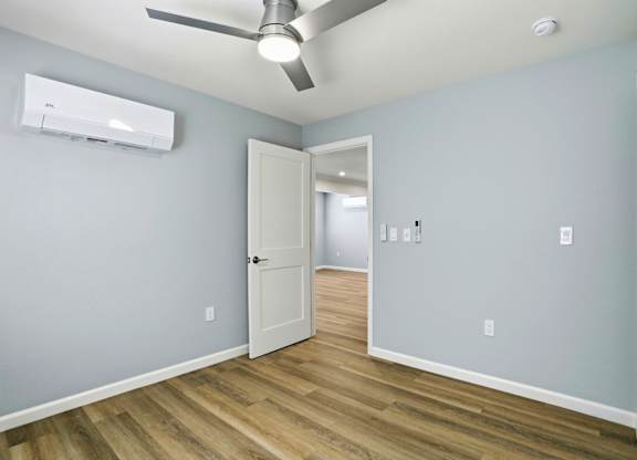 A room with a ceiling fan and a door leading to another room.