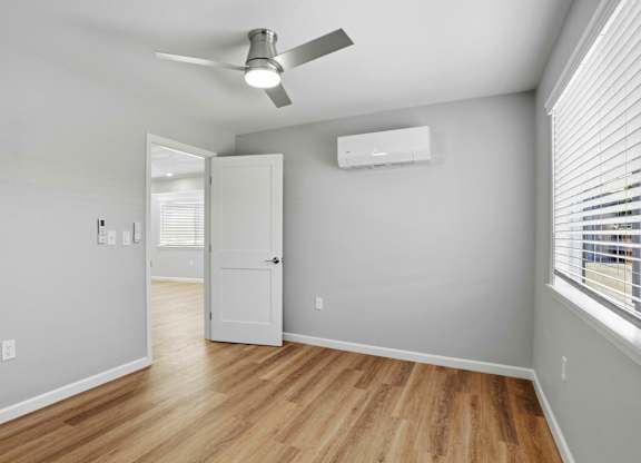 A room with a ceiling fan and a window with blinds.