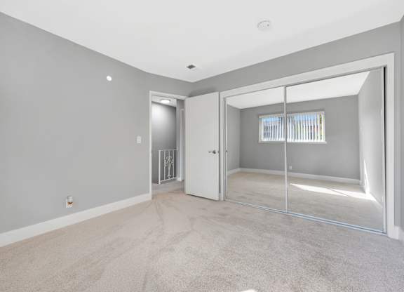 A room with a carpeted floor and a sliding glass door leading to a balcony.