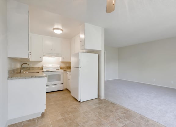 an empty kitchen with white cabinets and a white refrigerator