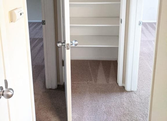 a closet with empty shelves and a door open