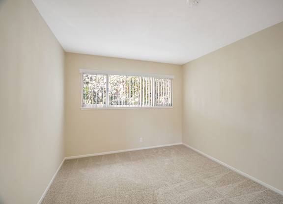 A room with a window covered by a white blind.