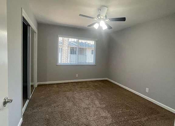 an empty room with a ceiling fan and a window