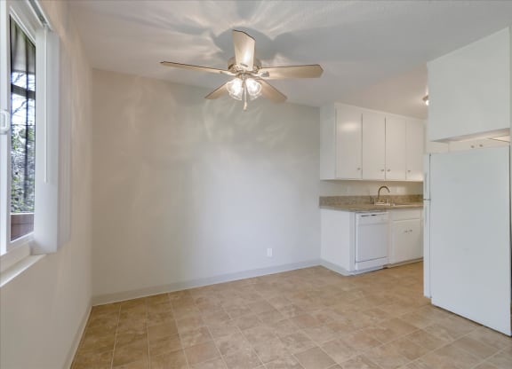 an empty kitchen with a ceiling fan and a window