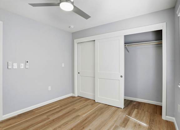 A room with a white door and a ceiling fan.