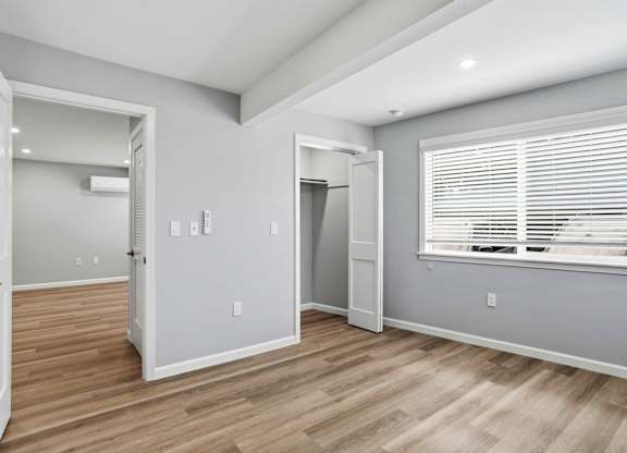 A room with a door, a window with blinds, and a wall with switches and outlets.