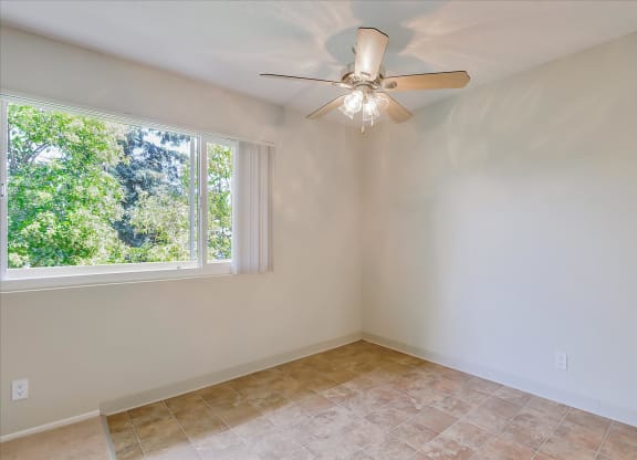 a living room with a large window and a ceiling fan