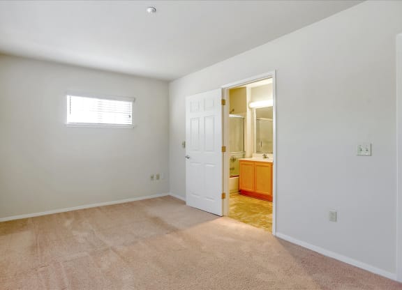 A room with a carpeted floor and a door leading to another room.