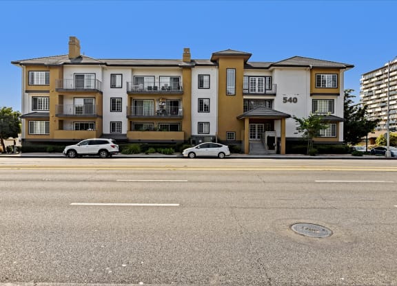 A street view of a building with cars parked in front.