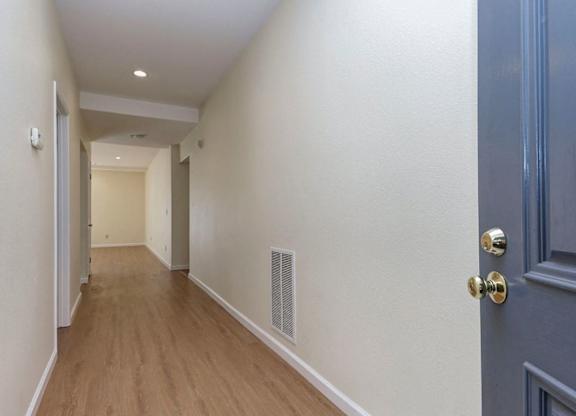 A long hallway with a blue door on the right.