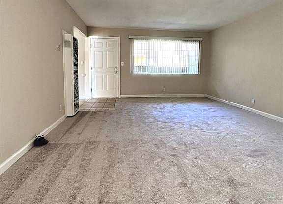 A room with a carpeted floor and a door leading to another room.