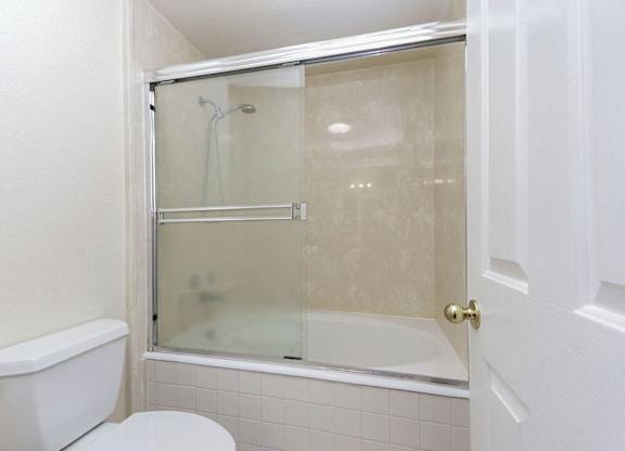 A white toilet sits next to a glass shower door in a bathroom.