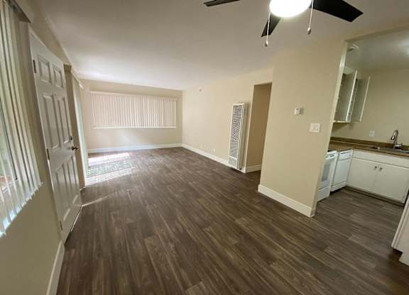 an empty living room and kitchen with wood flooring