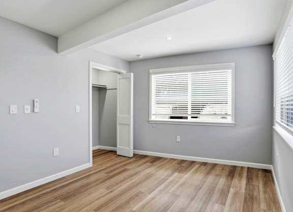 A room with a wooden floor and a window with blinds.