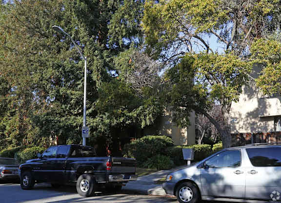 a parking lot with cars and trees in front of a building