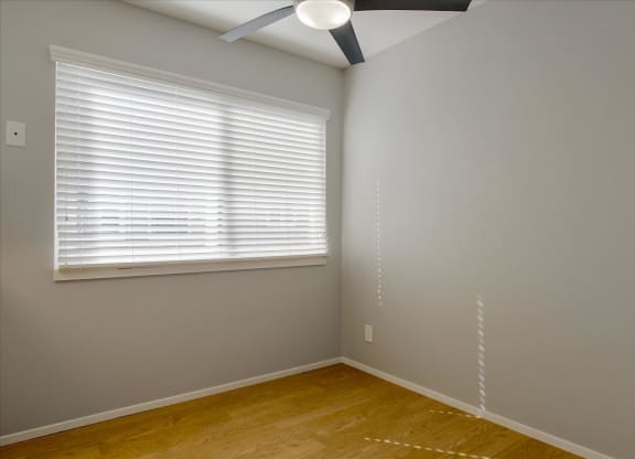 a bedroom with wood floors and a window and a ceiling fan