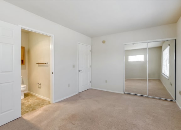 A white room with a carpeted floor and a glass door leading to another room.