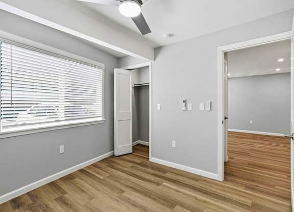 A room with a window, wooden floor, and a white door.