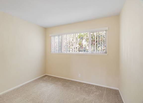 A room with a window covered by white blinds.