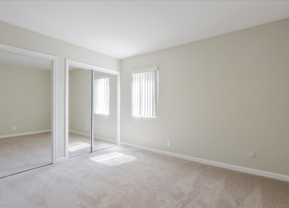 a bedroom with a mirrored closet and a carpeted floor