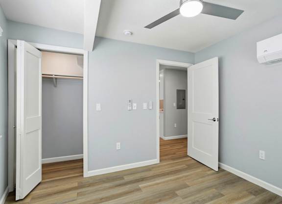 A room with a ceiling fan and a doorway leading to another room.