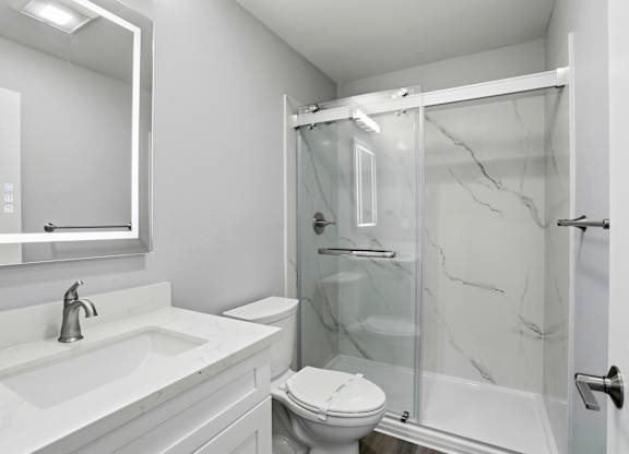 A white bathroom with a marble shower.