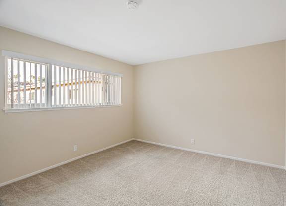 A room with a window and carpeted floor.