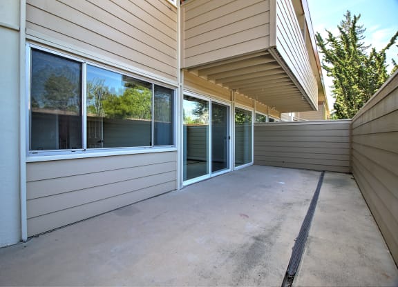 A patio area with a sliding glass door and a concrete floor.