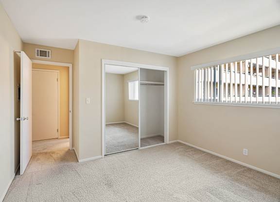 A room with a carpeted floor and a window with blinds.