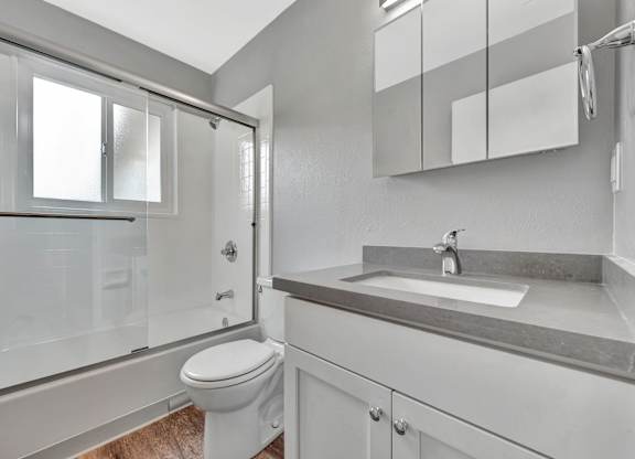 A white bathroom with a toilet, sink, and shower.