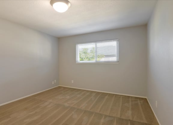 an empty living room with a window and wooden floors