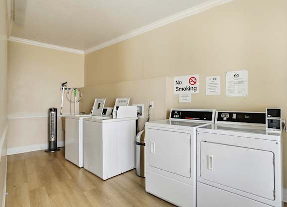 A laundry room with a washer, dryer, and ironing board.