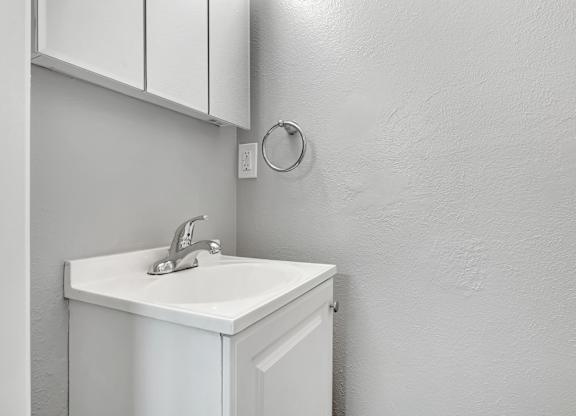A white sink is mounted under a white cabinet.