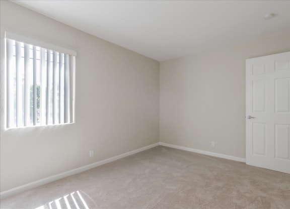 an empty bedroom with a white door and window