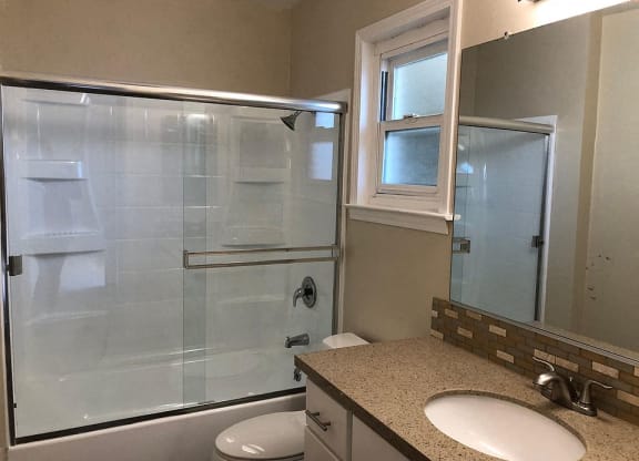 a bathroom with a shower and a sink and a toilet