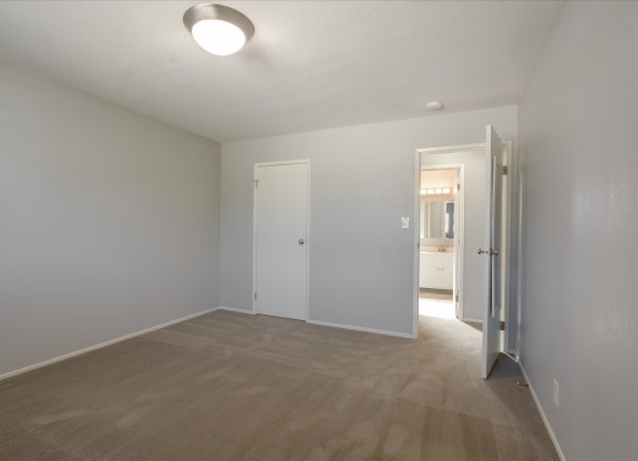 a empty living room with white walls and a door to a bathroom