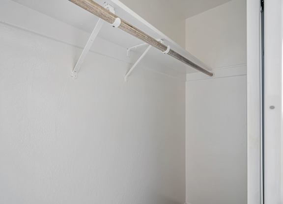 A white wall with a white door and a white shelf.