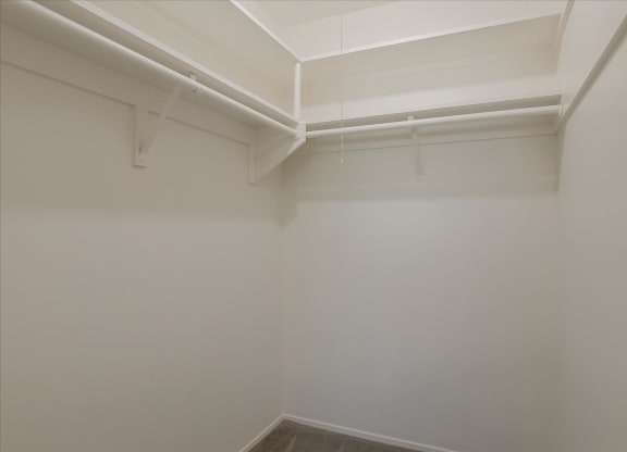 a closet with white walls and a white rack on the ceiling