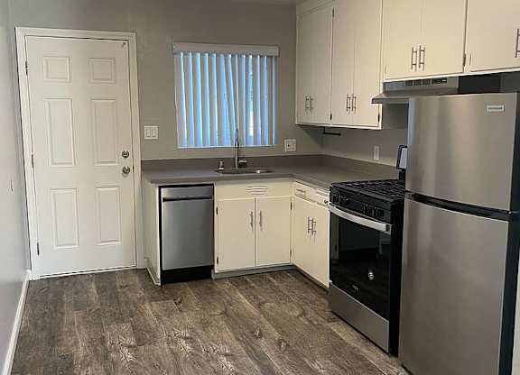 A kitchen with a refrigerator, oven, and sink.