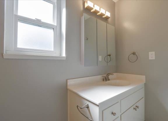 a bathroom with a sink and a mirror and a window