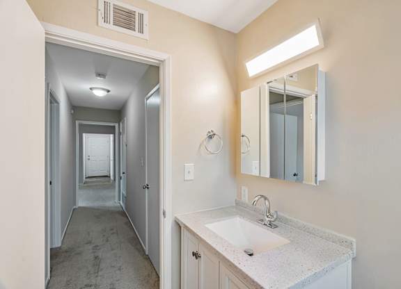 A bathroom with a sink, mirror, and light.