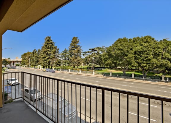 A balcony overlooks a busy street with cars and trees.