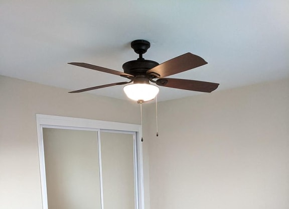 an empty room with a ceiling fan and a mirrored closet