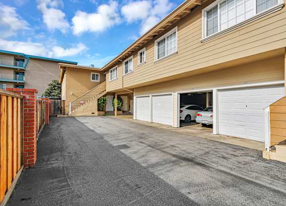 A sunny day at a residential area with a car parked in the driveway.