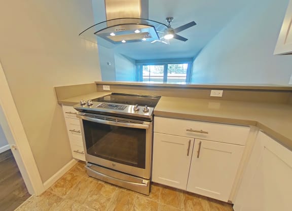 A kitchen with a stove top oven and a fan ceiling light.