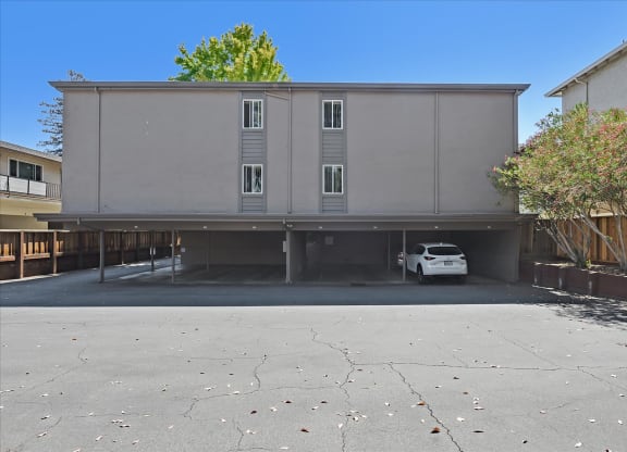 an empty parking lot with a white car parked under a building