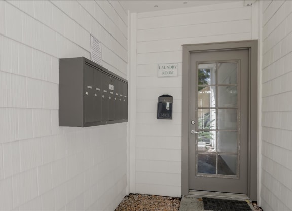 the front door of a white building with a glass door and a mailbox