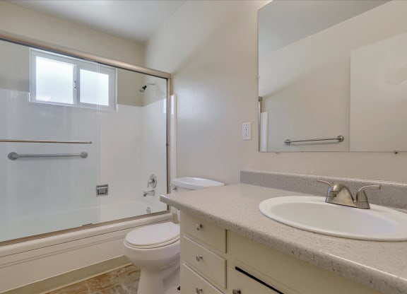 A white toilet sits in a bathroom next to a sink.